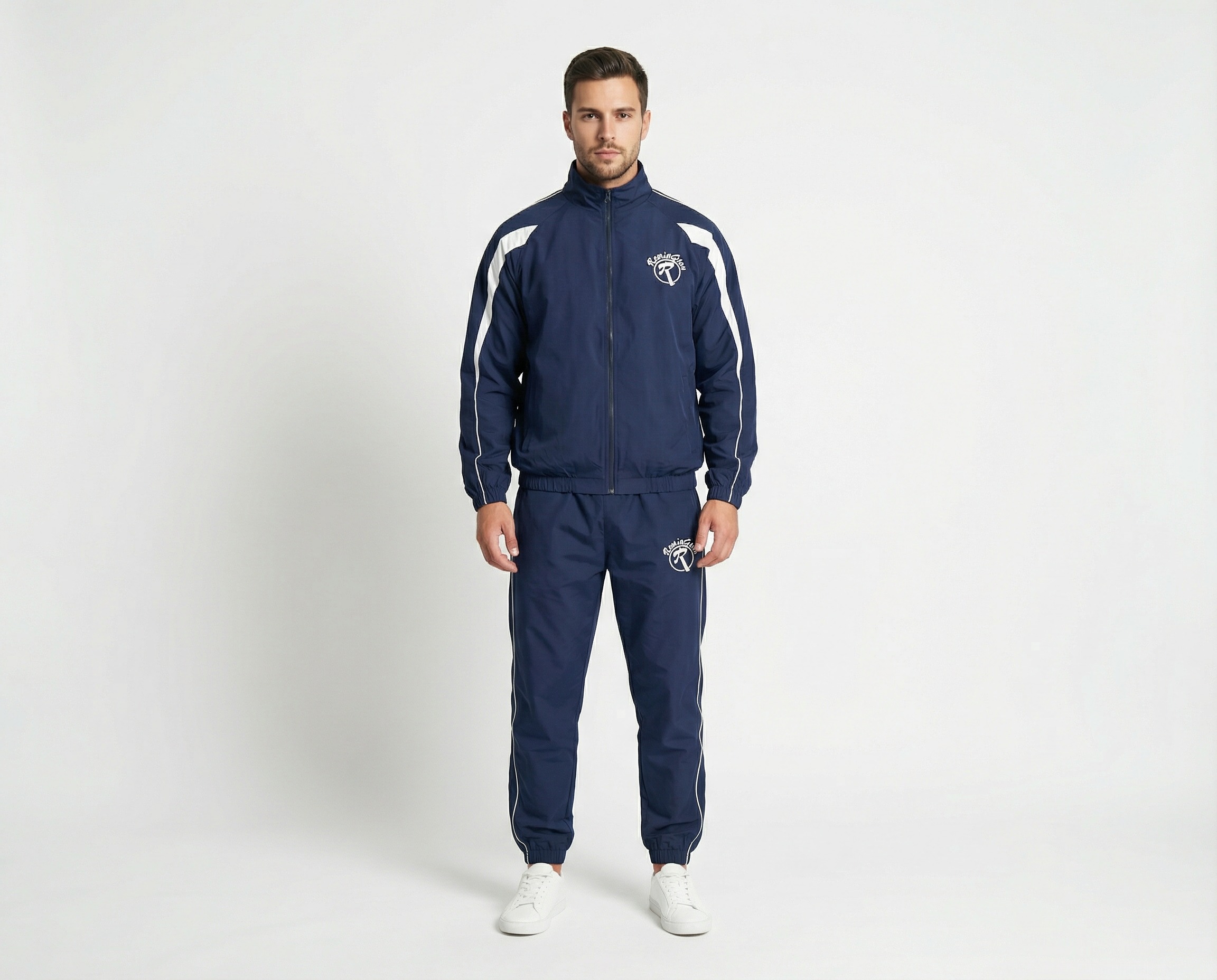 Male model wearing a navy blue training tracksuit with white shoulder panels, full-zip jacket, white Remington logos and matching athletic pants