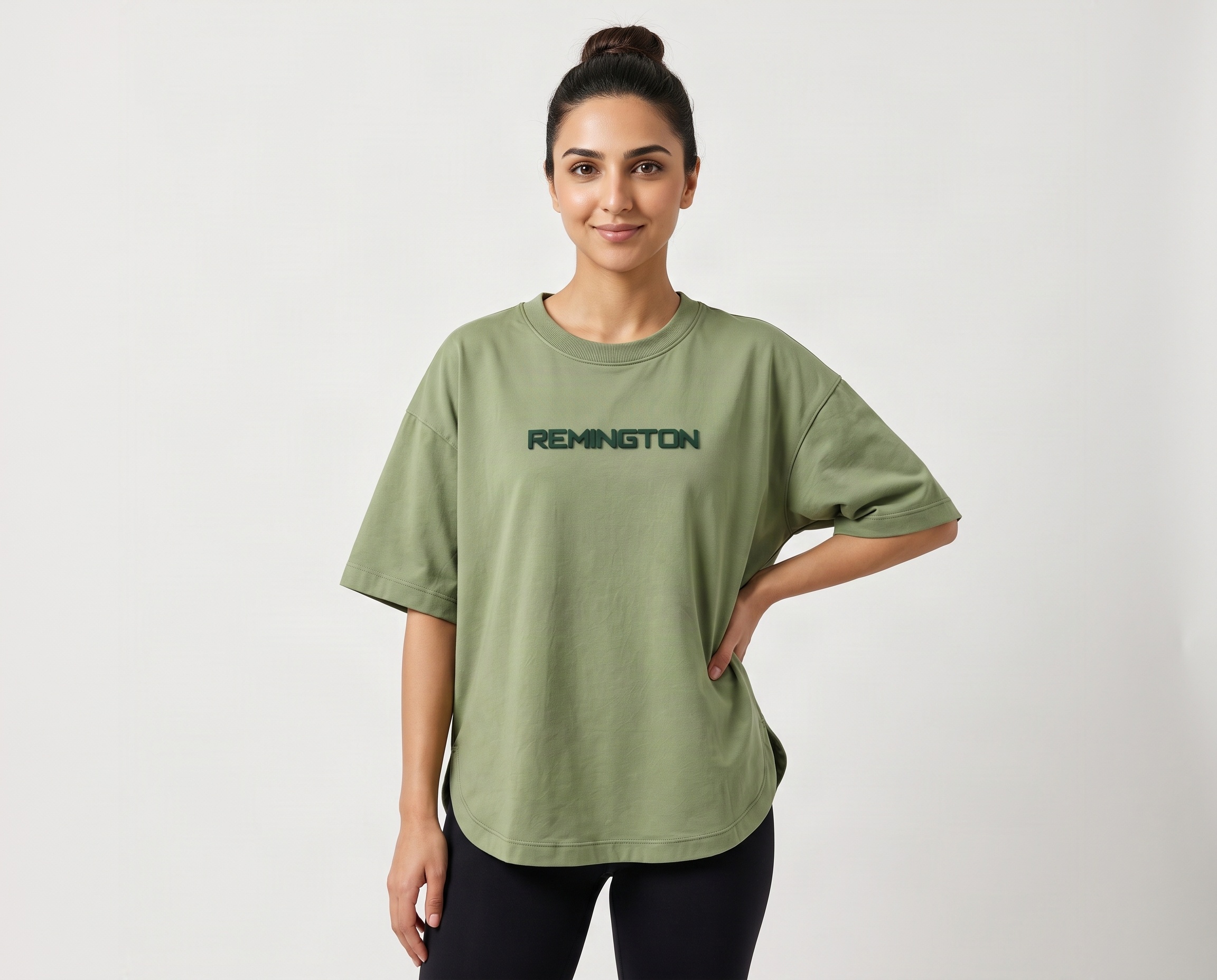 Front view of women's sage-green oversized T-shirt featuring dark-green REMINGTON chest branding and ribbed crew neck
