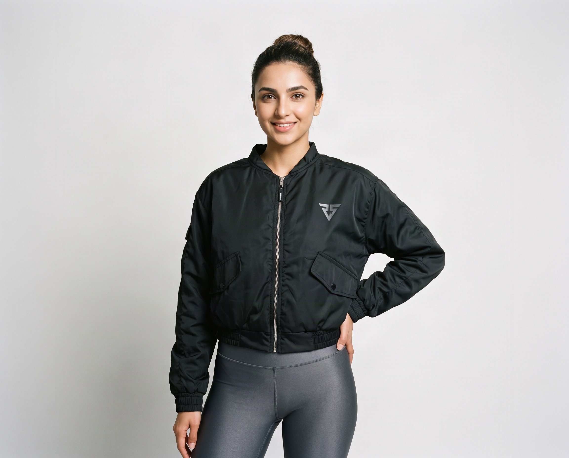 Women's black cropped bomber jacket with front zipper, angled flap pockets, elasticated hem and grey chest logo